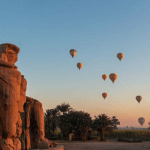 Colossi of Memnon at dawn with hot air balloons in the sky Luxor Egypt.jpg