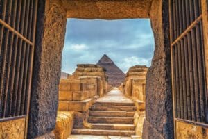 A view of the Great Pyramid of Giza framed by an ancient stone doorway, experienced during a private, custom-tailored tour with Top Class Egypt Travel.