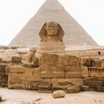 Frontal view of the Great Sphinx of Giza with the Pyramids in the background under a clear sky, Cairo, Egypt.