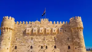 Exterior view of the historic Citadel of Qaitbay fortress in Alexandria, Egypt against a clear blue sky