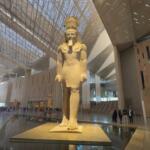 The colossal statue of King Ramses II standing in the grand atrium of the Grand Egyptian Museum (GEM) with modern architectural interior.