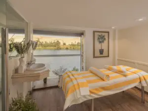 Massage treatment bed with yellow striped towel facing a picture window overlooking the Nile