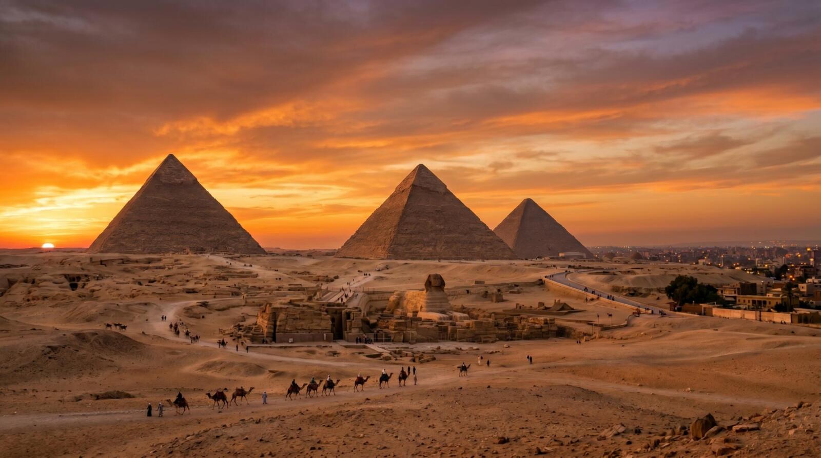 Wide-angle panoramic view of the three Great Pyramids of Giza and the Sphinx under a vibrant orange and purple sunset sky.