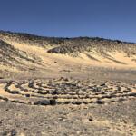 A spiral pattern made of dark volcanic stones laid on the sand in the Black Desert, Egypt