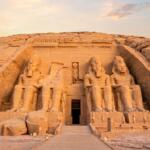 Colossal statues of Ramses II at the Abu Simbel temples carved into the sandstone cliff in Aswan Egypt at golden hour sunrise