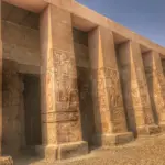Detail view of the massive stone columns and intricate relief carvings at the Temple of Abydos, Egypt, featuring strong side lighting and a perspective view, as seen on a Top Class Egypt Travel private excursion.