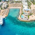 Aerial view of a luxury Red Sea beach resort in Egypt with turquoise waters, yachts, and sandy beaches.