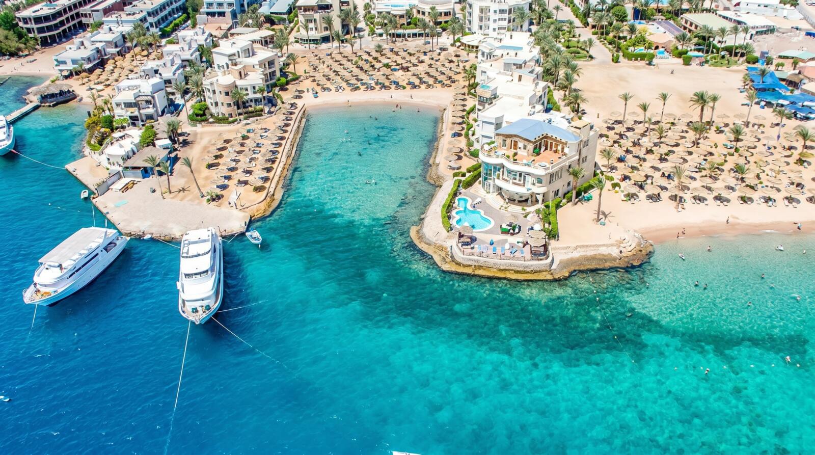 Aerial view of a luxury Red Sea beach resort in Egypt with turquoise waters, yachts, and sandy beaches.