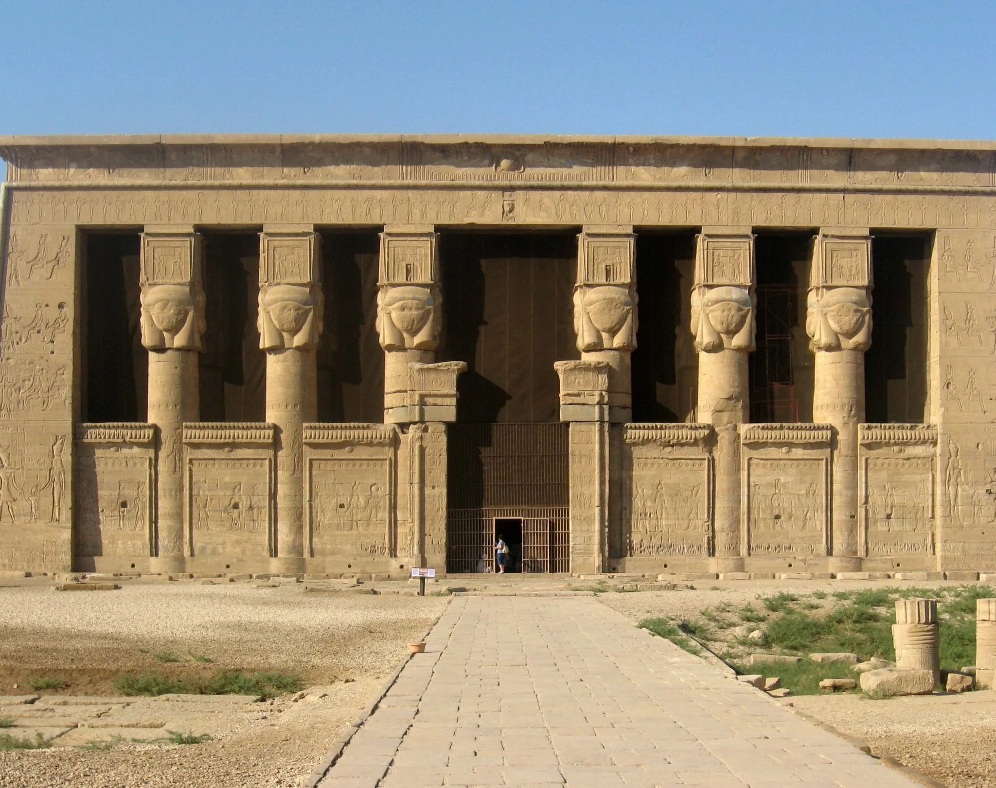 A symmetrical, detailed view of the monumental Temple of Hathor facade at Dendera, featuring famous Hathor-headed columns, optimized for exclusive tours by Top Class Egypt Travel.