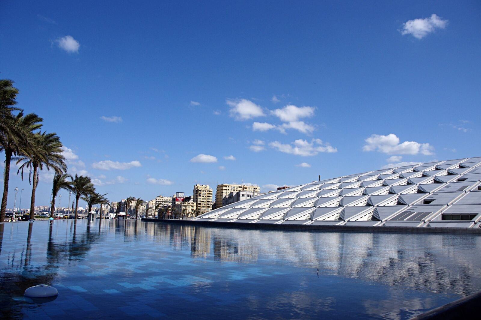 The modern exterior of the Bibliotheca Alexandrina reflecting in water, one of the top things to do in Alexandria, Egypt
