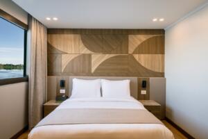 Frontal shot of king-size bed with geometric wooden headboard and dual nightstands on Jubal Dahabiya